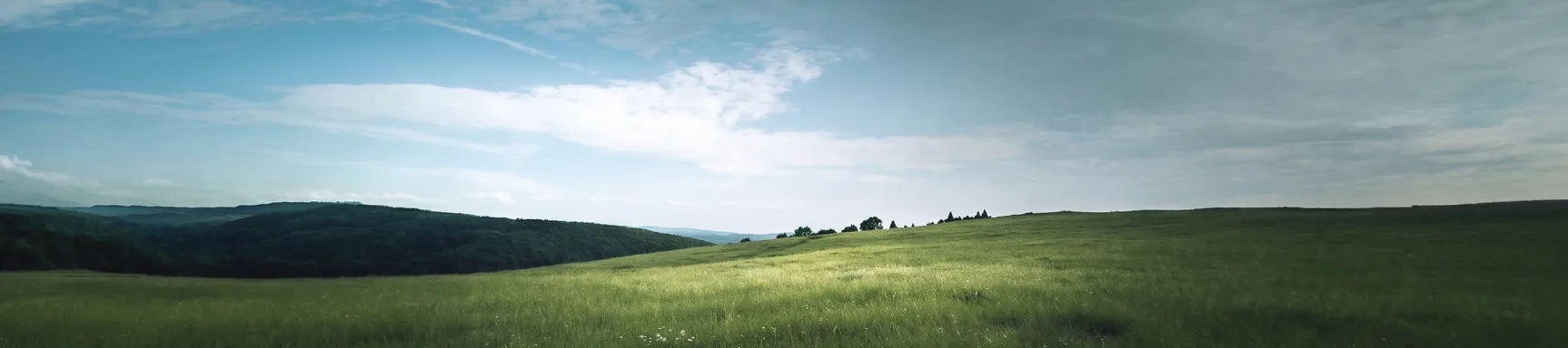 A mirrored cube standing in an open meadow under a wide sky